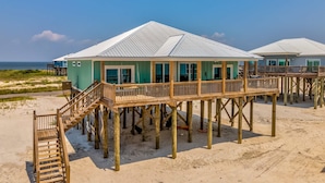 A beach house with a wooden deck and a view of the ocean. - Exquisite oceanfront beach home with hot tub, central AC, balcony, & W&D (Dauphin Island)