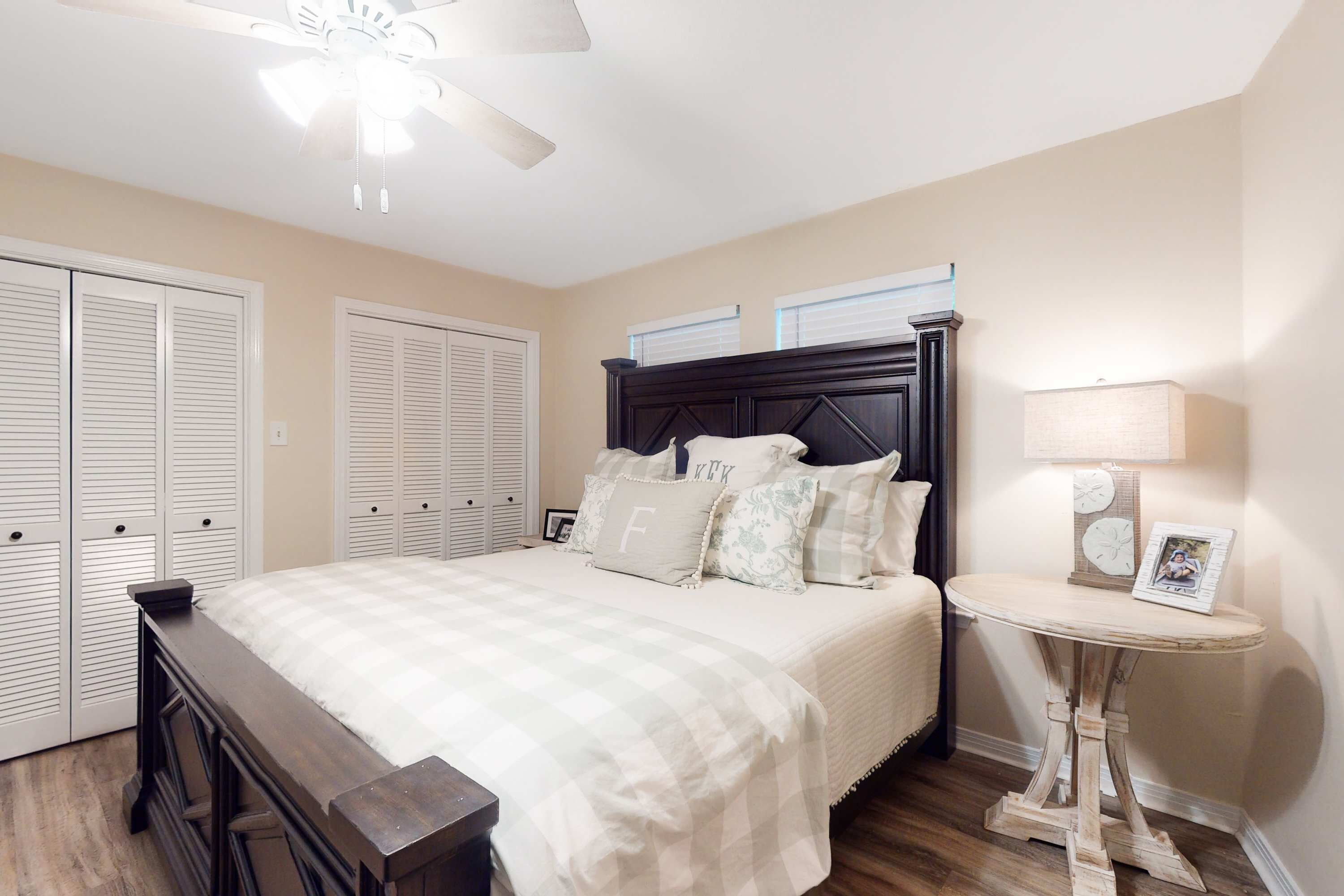 A bedroom with a bed, a nightstand, a bedside table, a ceiling fan, and a window.