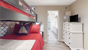 Ein Schlafzimmer mit Etagenbett, Kommode, Fernseher und Ventilator.