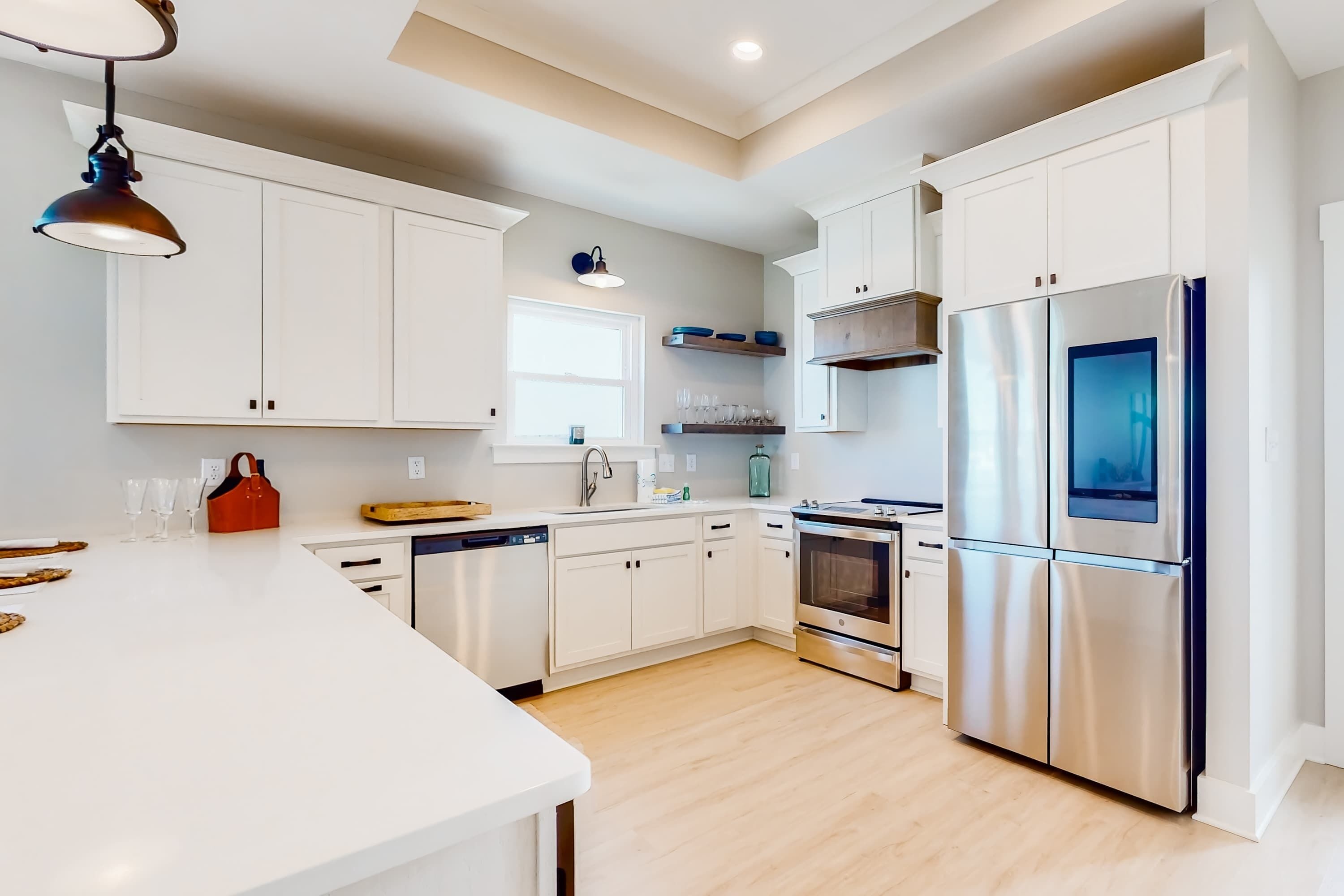 A modern kitchen with white cabinetry, a stainless steel refrigerator, and a large island.