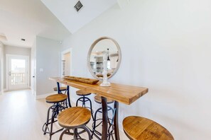Eine moderne Küche mit einer Holztresle und Hockern, einem großen Spiegel und Blick in den Essbereich.