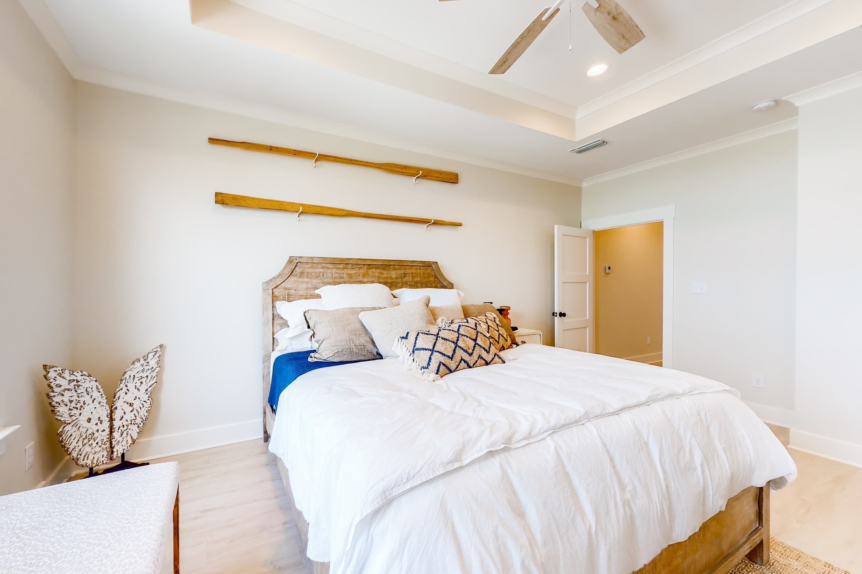 A bedroom with a bed, wooden headboard, and a ceiling fan.