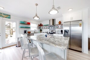 A modern kitchen with a central island, stainless steel appliances, and white cabinetry. - Bay view home with WiFi, central ac, & decks - snowbirds, dogs welcome (Dauphin Island)