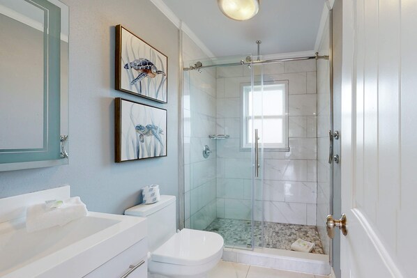 A bathroom with a glass-enclosed shower, a white toilet, and a sink. - Bay view home with WiFi, central ac, & decks - snowbirds, dogs welcome (Dauphin Island)