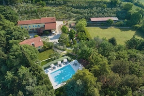 An aerial view of a property with a swimming pool, multiple buildings, and surrounding greenery. - LAKE GARDA SWEET HOME CASON DEGLI ULIVI (Rivoli Veronese)