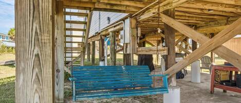 A wooden structure with a blue bench under a roof, surrounded by a grassy area.
