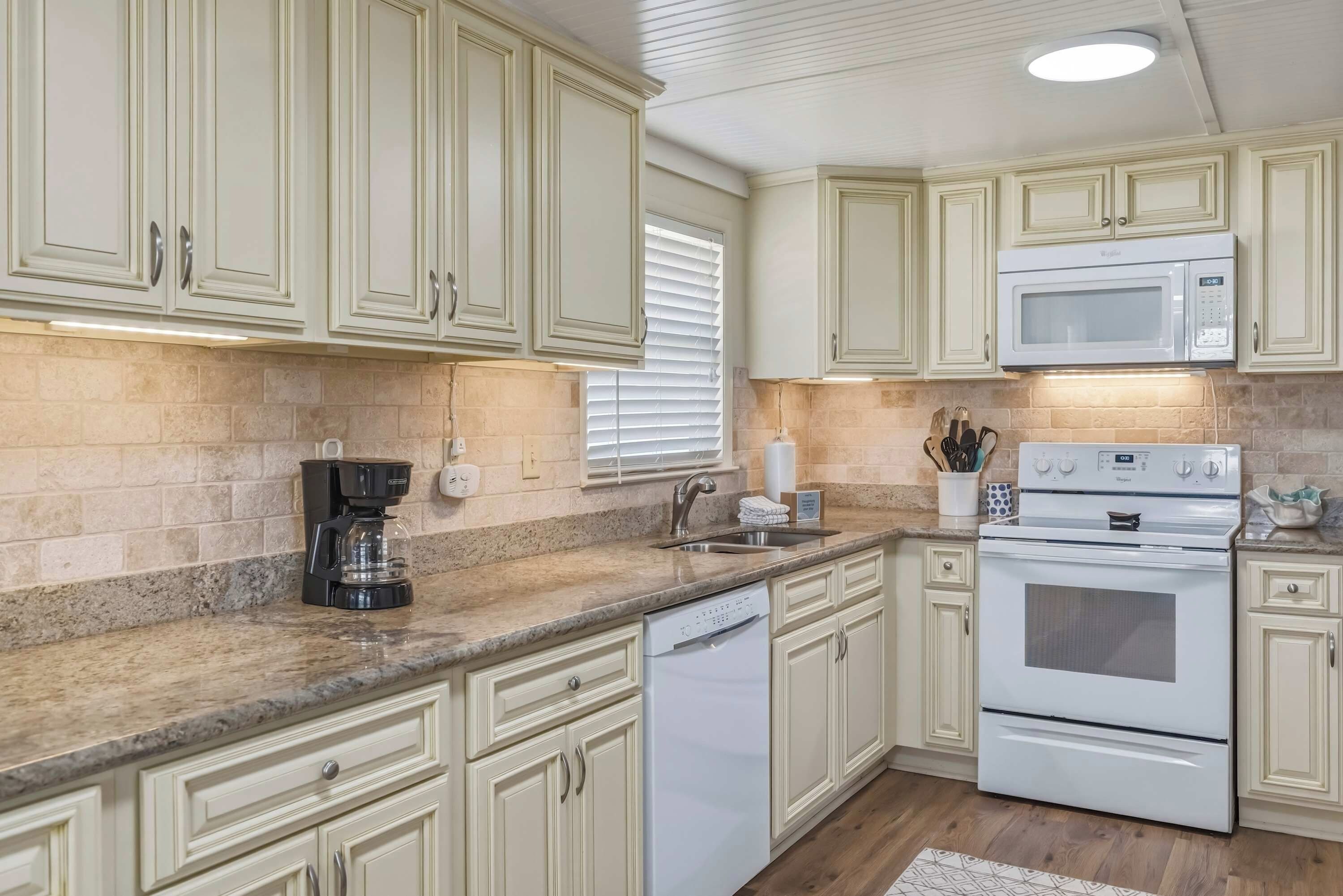 A kitchen with white cabinets, a built-in microwave, a coffee maker, and a dishwasher.