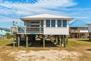 A two-story building with a balcony, a sign indicating 'vacasa', and a clear sky. - Dog-friendly house on Dauphin Island, Near beach access, Patio, Grill, Washer & Dryer (Dauphin Island)