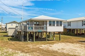 A two-story building with a balcony, a sign for 'Vacasa', and a street sign for 'Aristotle's Lanterman'. - Dog-friendly house on Dauphin Island, Near beach access, Patio, Grill, Washer & Dryer (Dauphin Island)