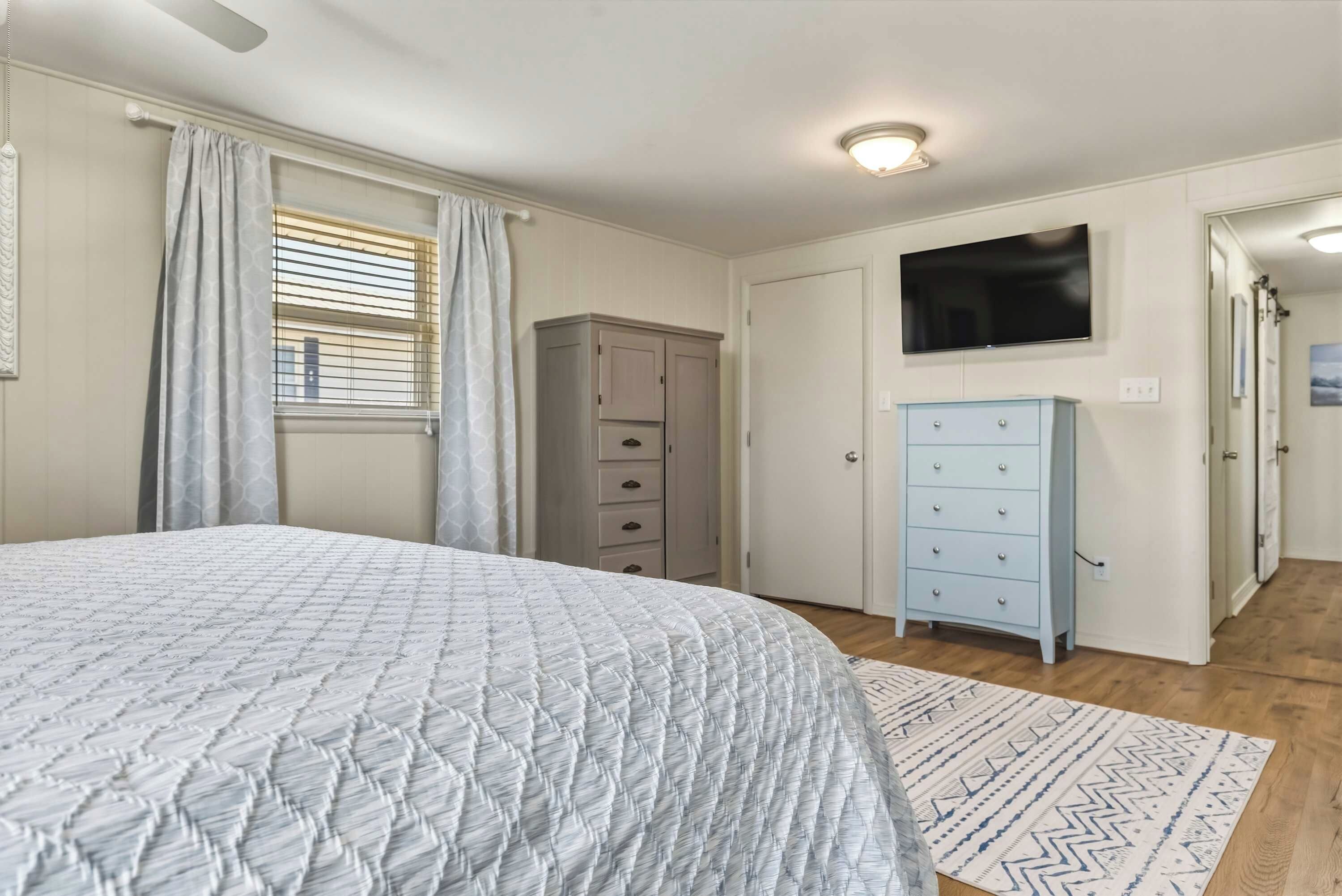 Een slaapkamer met een bed, een kledingkast, een televisie en een raam met gordijnen.