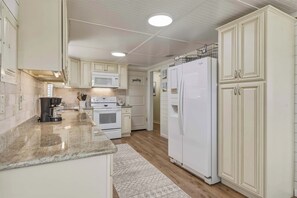 A kitchen with white cabinets, a refrigerator, a microwave, and a coffee maker. - Dog-friendly house on Dauphin Island, Near beach access, Patio, Grill, Washer & Dryer (Dauphin Island)