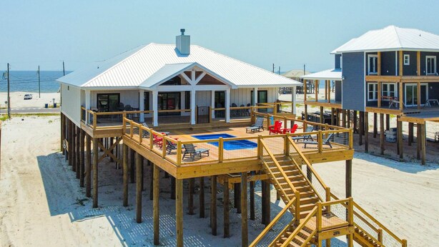 Um imóvel à beira-mar com um deck de madeira, piscina e área de estar coberta.