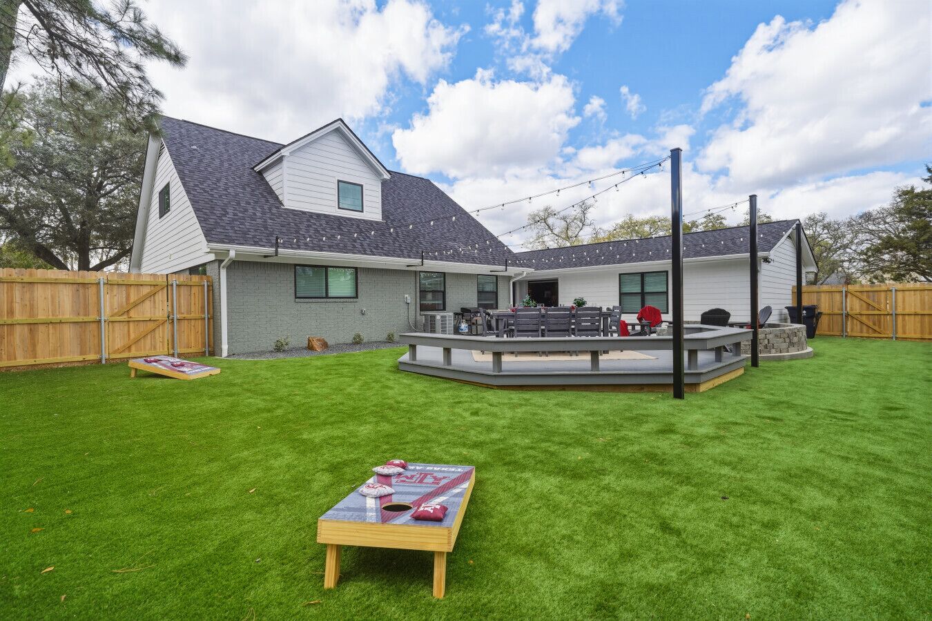 Un jardin arrière aménagé pour une maison d’habitation, avec une terrasse, un espace barbecue et une pelouse bien entretenue.