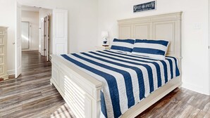A bedroom with a bed, a nightstand, a lamp, and a sign on the wall. - Coastal dog-friendly home with grill, balcony, & patio - short walk to the beach (Dauphin Island)