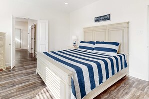 A bedroom with a bed, a nightstand, a lamp, and a sign on the wall. - Coastal dog-friendly home with grill, balcony, & patio - short walk to the beach (Dauphin Island)