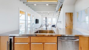 Una cocina moderna con un lavamanos de acero inoxidable, armarios de madera y vistas a la ciudad.