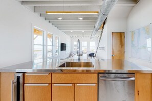 A modern kitchen with a stainless steel sink, wooden cabinets, and a view of the city. - Gulf Front Paradise - Swim Spa, Dolphin Spotting, and Beach at Your Doorstep (Dauphin Island)