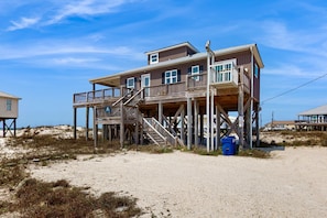 Ein zweistöckiges Holzhaus mit Balkon, direkt an einem Sandstrand gelegen.