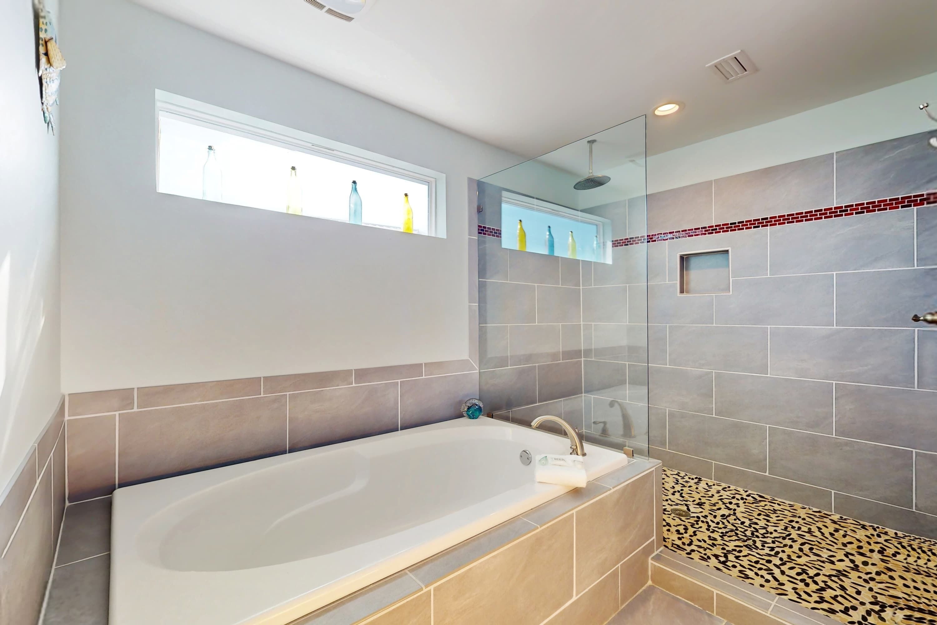 Un baño con bañera, ducha y paredes de azulejos.