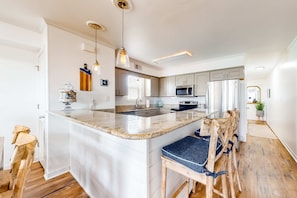 A modern kitchen with a central island, wooden chairs, and pendant lighting. - Lagoon-view duplex with free WiFi, deck, & private washer/dryer - dog-friendly (Gulf Shores)