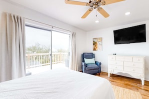 A bedroom with a bed, a chair, a TV, and a dresser. - Lagoon-view duplex with free WiFi, deck, & private washer/dryer - dog-friendly (Gulf Shores)