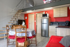 A modern kitchen with a stainless steel refrigerator, wooden cabinets, and a red wall.