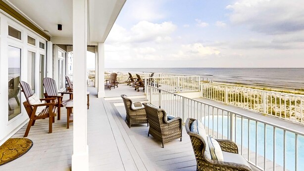 En balkon med fletmøbler, en pool og udsigt til stranden.