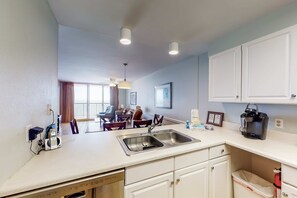 A modern kitchen with a built-in dishwasher, a sink, and a coffee maker. - Beachfront Balcony with Million-Dollar Views, Shared Pool, WiFi, Washer & Dryer (Gulf Shores)