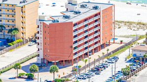 A multi-story hotel with a parking lot and beach view. - Beachfront Balcony with Million-Dollar Views, Shared Pool, WiFi, Washer & Dryer (Gulf Shores)
