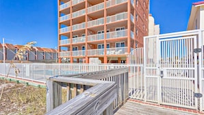 A multi-story building with balconies, a wooden deck, and a gated entrance. - Beachfront Balcony with Million-Dollar Views, Shared Pool, WiFi, Washer & Dryer (Gulf Shores)