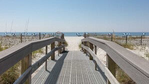 A wooden boardwalk leading to a sandy beach with a clear sky. - Coastal Condo w Balcony & Shared Pools, Hot Tubs, Gym and Gulf views (Gulf Shores)