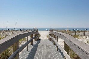 A wooden boardwalk leading to a sandy beach with a clear sky. - Coastal Condo w Balcony & Shared Pools, Hot Tubs, Gym and Gulf views (Gulf Shores)