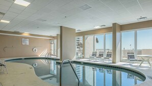 A swimming pool with a curved edge, a lifeguard chair, and a sun terrace with chairs. - Coastal Condo w Balcony & Shared Pools, Hot Tubs, Gym and Gulf views (Gulf Shores)
