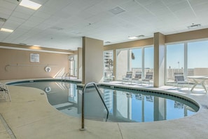 A swimming pool with a curved edge, a lifeguard chair, and a sun terrace with chairs. - Coastal Condo w Balcony & Shared Pools, Hot Tubs, Gym and Gulf views (Gulf Shores)