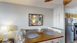 Uma sala de jantar com uma mesa de madeira, cadeiras brancas e um espelho decorativo.