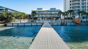 Visão nítida de uma piscina com uma passarela que leva a um edifício com varandas.