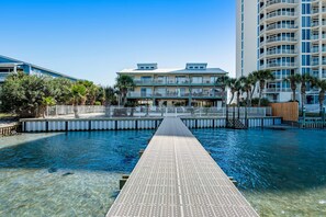 A clear view of a swimming pool with a walkway leading to a building with balconies. - Tropically decorated condo in gulf-side complex w/shared pool, central AC, WiFi (Gulf Shores)