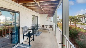 Varanda com mesa, cadeiras, porta de vidro e vista para a rua.