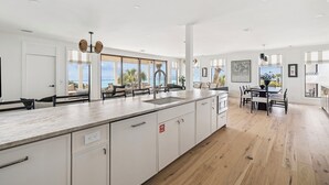 A modern kitchen with a large island, white cabinetry, and a view of the ocean. - Sandpiper's Retreat|Gulf Front|Private Pool|Golf Cart (Santa Rosa Beach)