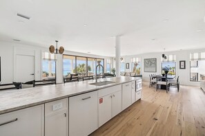 A modern kitchen with a large island, white cabinetry, and a view of the ocean. - Sandpiper's Retreat|Gulf Front|Private Pool|Golf Cart (Santa Rosa Beach)