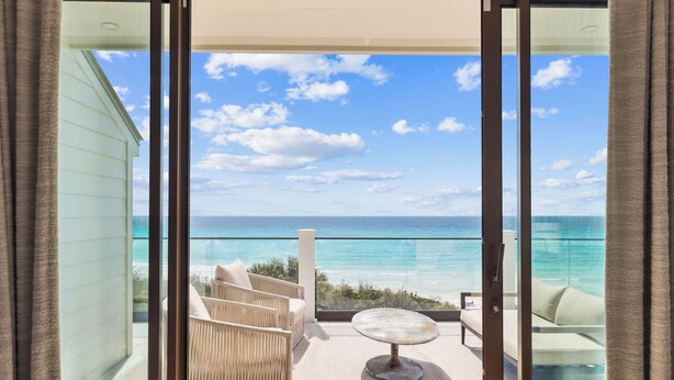 A balcony with a view of the ocean, wicker furniture, and a round table. - Sandpiper's Retreat|Gulf Front|Private Pool|Golf Cart (Santa Rosa Beach)