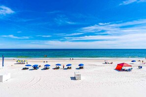 En strand med hvidt sand, klar blå himmel og roligt hav.