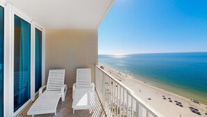 A balcony with white lounge chairs, a view of a beach, and a clear sky. - Gulf-front condo with pool, sauna, washer,dryer, cable, & central AC (Gulf Shores)