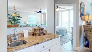 A modern bathroom with a granite countertop, a sink, and a mirror. - Gulf-front condo with pool, sauna, washer,dryer, cable, & central AC (Gulf Shores)