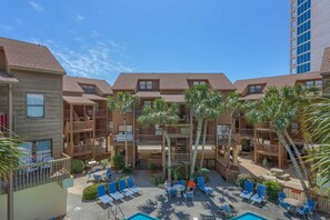 A multi-story hotel with balconies, outdoor seating, and a pool area. - Lofty Condo in a Beachfront Complex w/ WiFi, AC, Balcony & Shared Outdoor Pool (Gulf Shores)