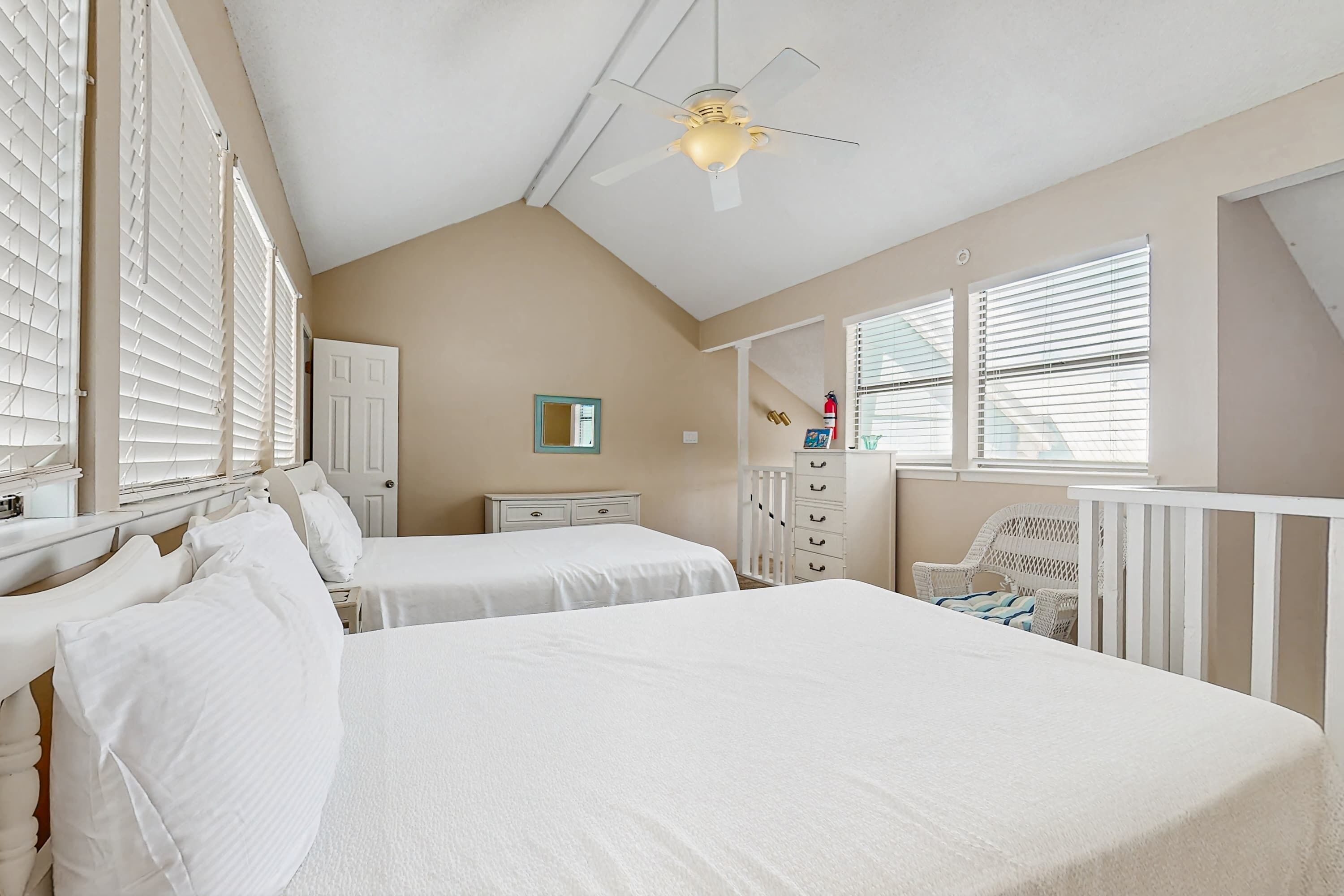 Ein Schlafzimmer mit zwei Betten, einem Deckenventilator, einem Kinderbett und einer Kommode.