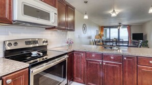 A kitchen with a microwave, stove, oven, and granite countertop. - Gulf front condo with beach views, pools & free WiFi (Orange Beach)