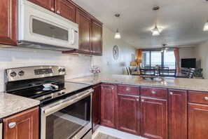 A kitchen with a microwave, stove, oven, and granite countertop. - Gulf front condo with beach views, pools & free WiFi (Orange Beach)