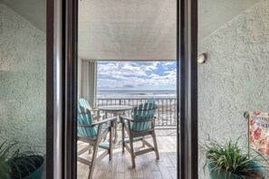 A balcony with a wooden floor, two chairs, and a table. - Gulf front condo with beach views, pools & free WiFi (Orange Beach)