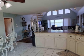 Una cocina con isla central, muebles blancos y vista al agua.